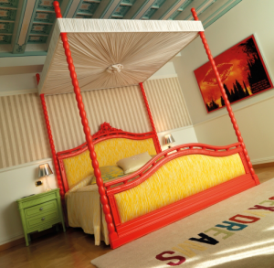 Una zona notte in cui sono utilizzati i colori caldi: rosso e giallo per il letto. (Byblos)