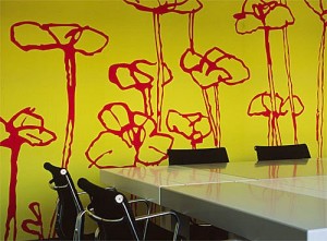 Soluzione per una tappezzeria murale dalle tinte decise giallo con  grandi fiori rossi ideale in una zona living.