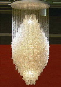 Lampada a sospensione con un grande cluster di dischi madre-perla. Attaccato da catene di anelli metallici di piccole dimensioni. Montato su piatto bianco soffitto in legno. 